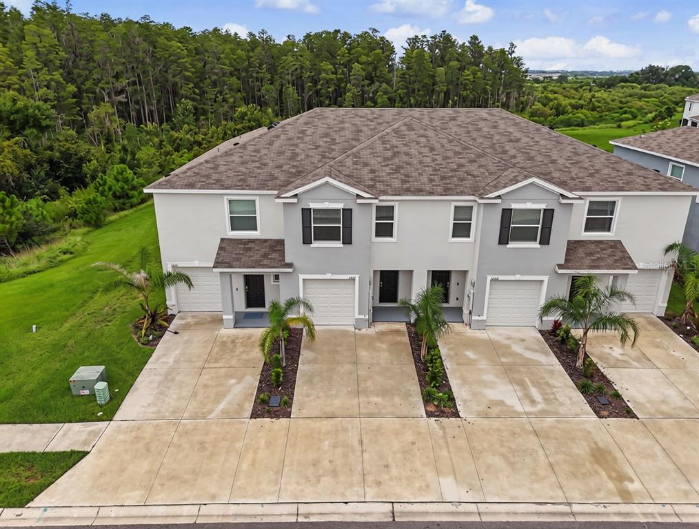 An exterior view of a two-story duplex with gray siding, shingled roofs, and concrete driveways — 32612 TURTLE GRACE LOOP, WESLEY CHAPEL, FL