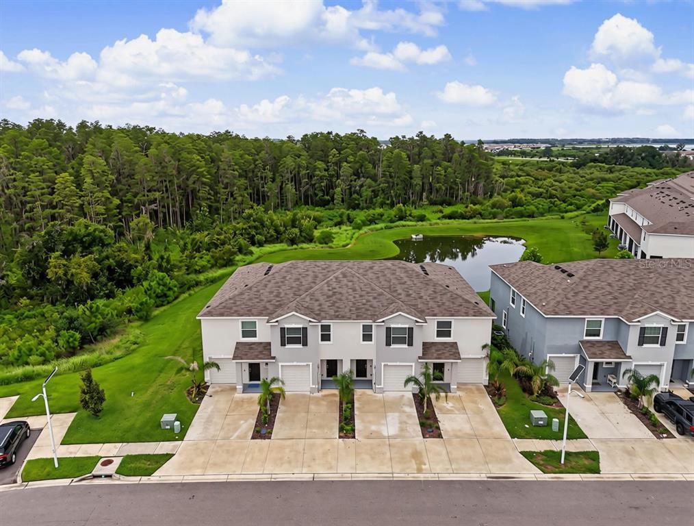 An aerial view of a two-story townhouse with a driveway and a pond behind it — 32612 TURTLE GRACE LOOP, WESLEY CHAPEL, FL