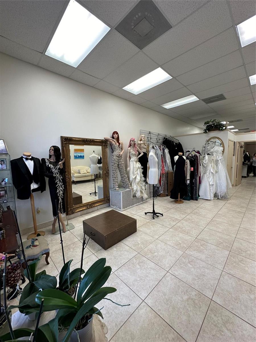 A retail clothing store features mannequins, formal wear, a large ornate mirror, and tiled flooring — CORAL SPRINGS, FL
