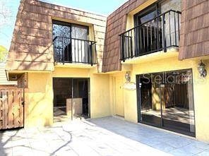 The exterior of a two-story townhouse features a tiled roof, balconies, and sliding glass doors — 5371 BAMBOO COURT UNIT 401, ORLANDO, FL