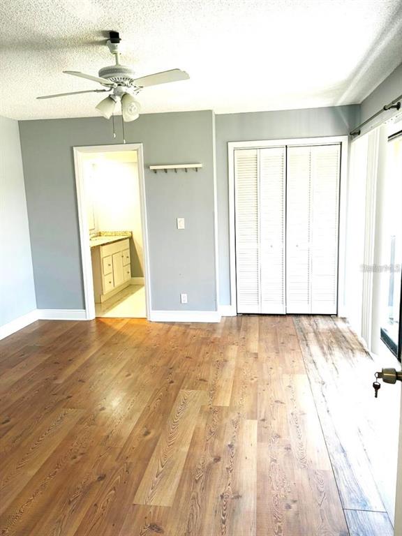 A bedroom features wood-look flooring, a ceiling fan, a closet with louvered doors, and an entryway — 5371 BAMBOO COURT UNIT 401, ORLANDO, FL