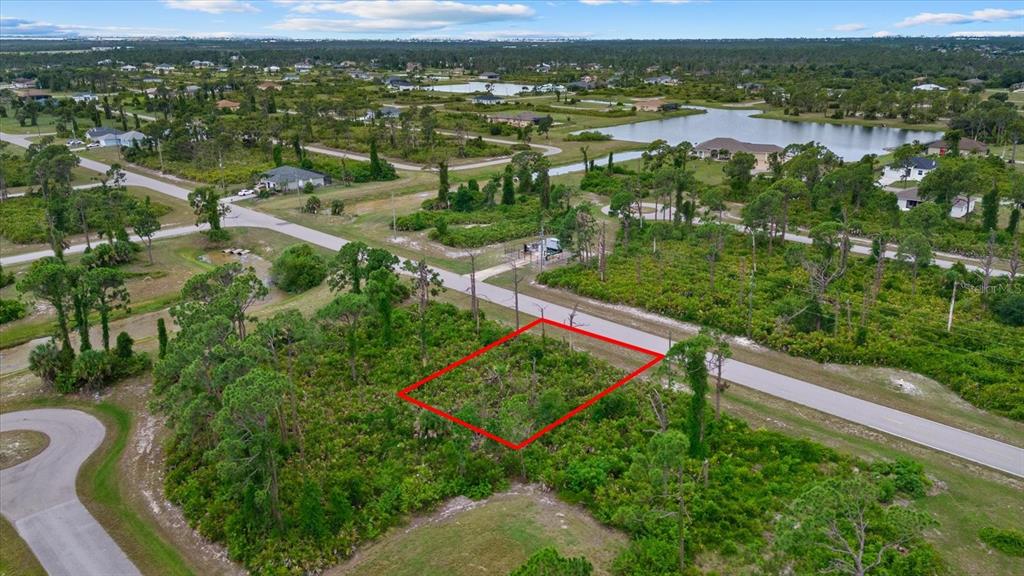 An aerial view shows a vacant, wooded residential lot outlined in red along a paved road — 49 MASTHEAD ROAD, PLACIDA, FL