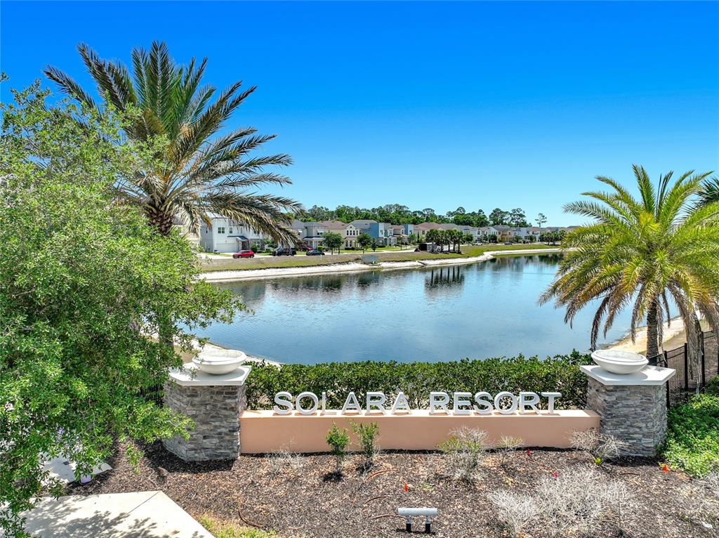 A stone monument sign for Solara Resort sits in front of a lake and houses — 8976 AMELIA DOWNS TRAIL, KISSIMMEE, FL