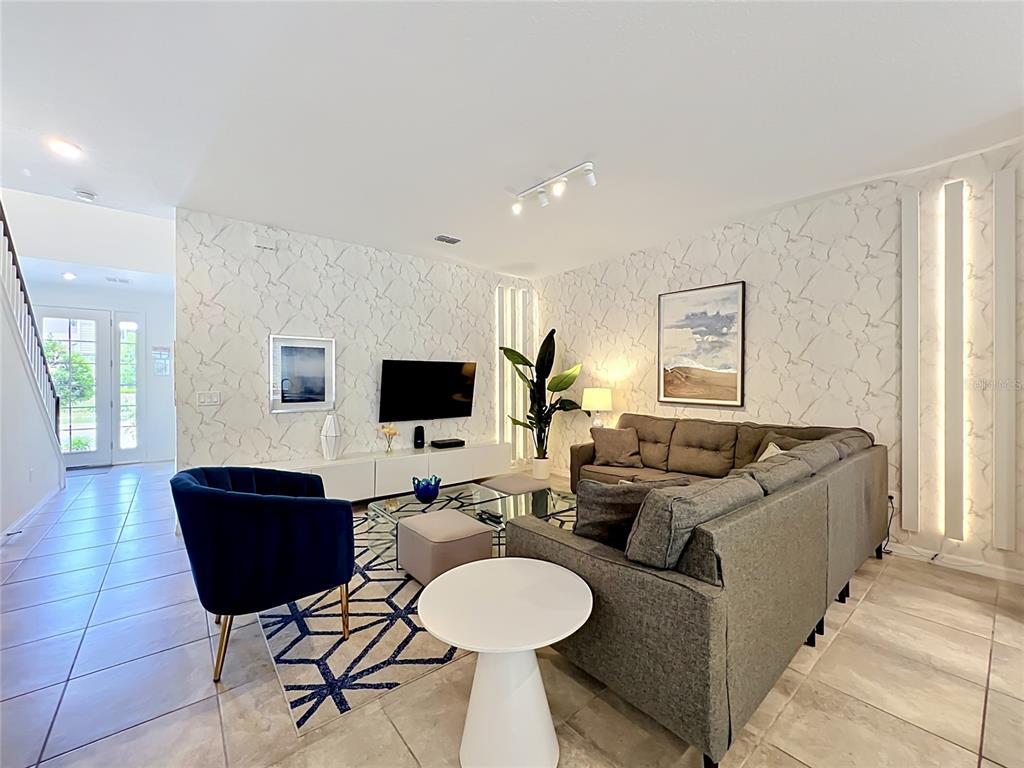 A living room features a sectional sofa, a blue armchair, and textured wallpaper — 8976 AMELIA DOWNS TRAIL, KISSIMMEE, FL
