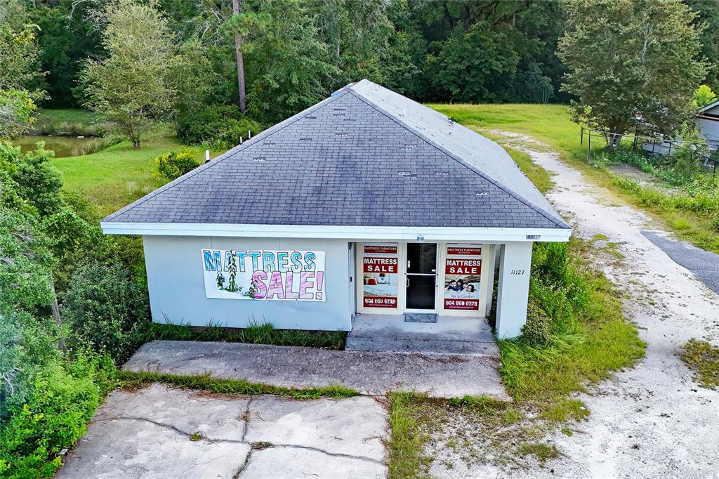 An aerial view shows a single-story commercial building with a gray roof and mattress sale signage — 11127 LEM TURNER ROAD, JACKSONVILLE, FL