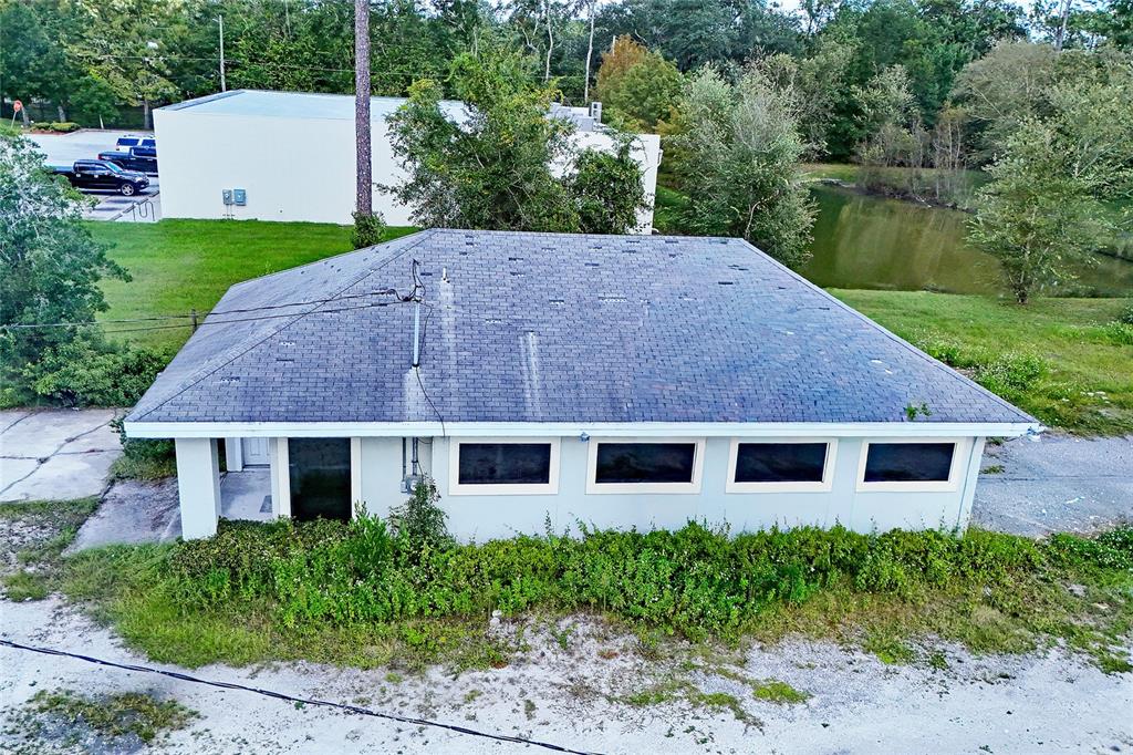An aerial view shows a single-story building with a dark shingled roof and overgrown landscaping — 11127 LEM TURNER ROAD, JACKSONVILLE, FL
