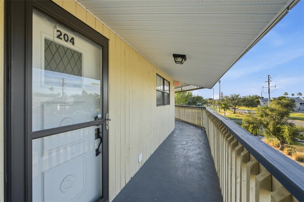 A covered exterior walkway leads to a door marked 204 with a wooden railing — 11650 CAPRI CIRCLE S UNIT 204, TREASURE ISLAND, FL