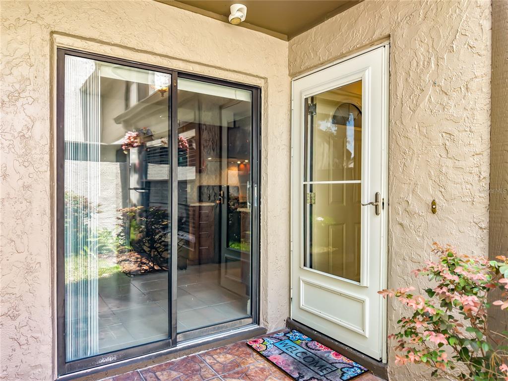 A sliding glass door and a white storm door lead into a home exterior — 1016 SHERRYWOOD STREET, CASSELBERRY, FL