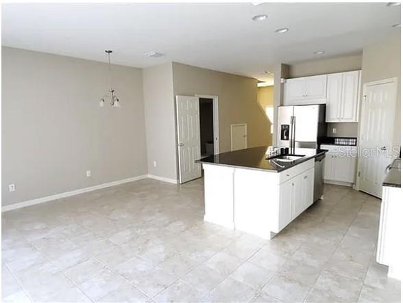 An open-concept kitchen with white cabinets, a dark island countertop, and light tile flooring — 7027 TOWNE LAKE ROAD, RIVERVIEW, FL