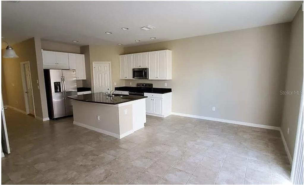 A kitchen features white cabinets, black countertops, stainless steel appliances, and a central island — 7027 TOWNE LAKE ROAD, RIVERVIEW, FL