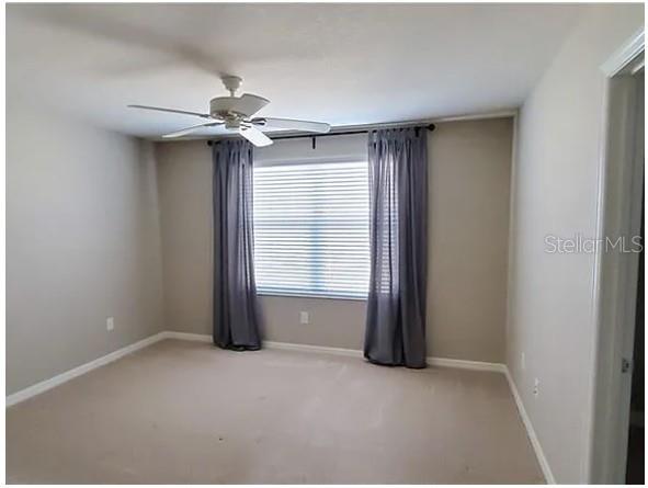 An empty bedroom with beige carpet, light gray walls, a ceiling fan, and gray curtains — 7027 TOWNE LAKE ROAD, RIVERVIEW, FL
