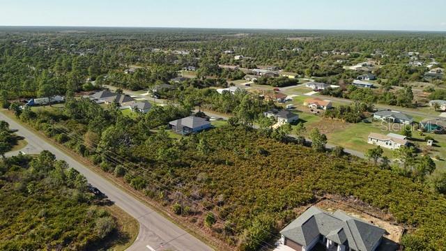 An aerial view shows a vacant lot surrounded by residential houses and wooded areas — 12154 ZITTLE AVENUE, PORT CHARLOTTE, FL