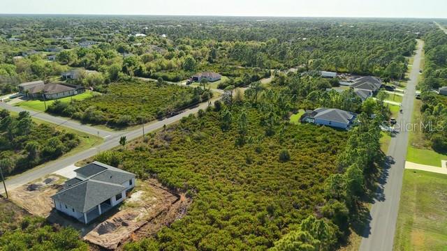 An aerial view shows a newly constructed house on a lot surrounded by dense vegetation — 12154 ZITTLE AVENUE, PORT CHARLOTTE, FL