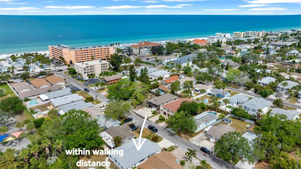 An aerial view shows a residential neighborhood near a beach with a white arrow pointing to a house — 121 10TH AVE, INDIAN ROCKS BEACH, FL