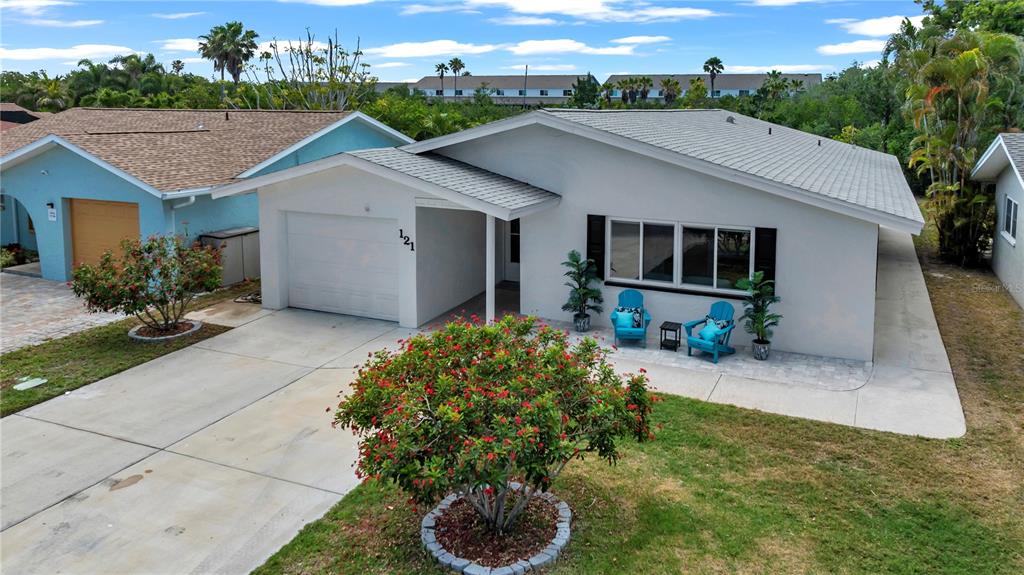 A single-story house with a white exterior, a garage, and two blue chairs on the porch — 121 10TH AVE, INDIAN ROCKS BEACH, FL