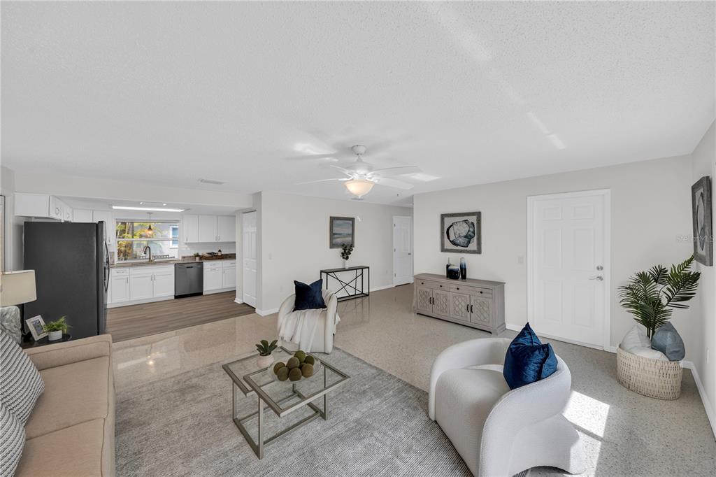 A living room with light tile floors, a gray area rug, and an open kitchen — 121 10TH AVE, INDIAN ROCKS BEACH, FL