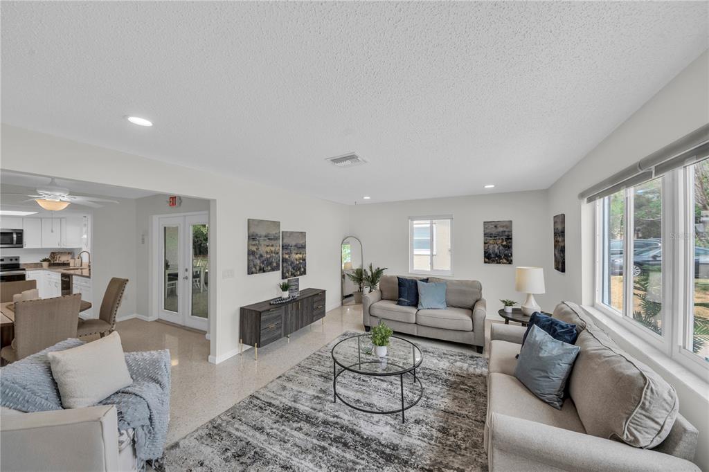 A bright living room features light-colored walls, tile flooring, a gray area rug, and furniture — 121 10TH AVE, INDIAN ROCKS BEACH, FL