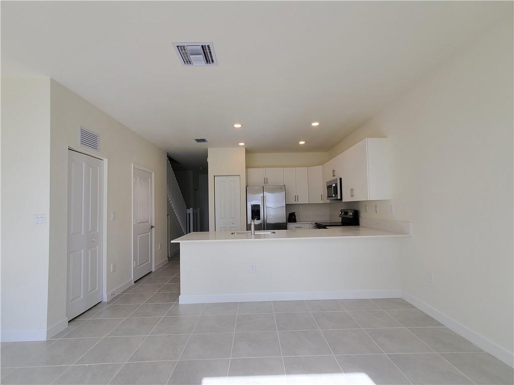 A kitchen with white cabinets, stainless steel appliances, and a breakfast bar on tile floors — 3216 W 114th Terrace, Hialeah FL 33018, HIALEAH, FL