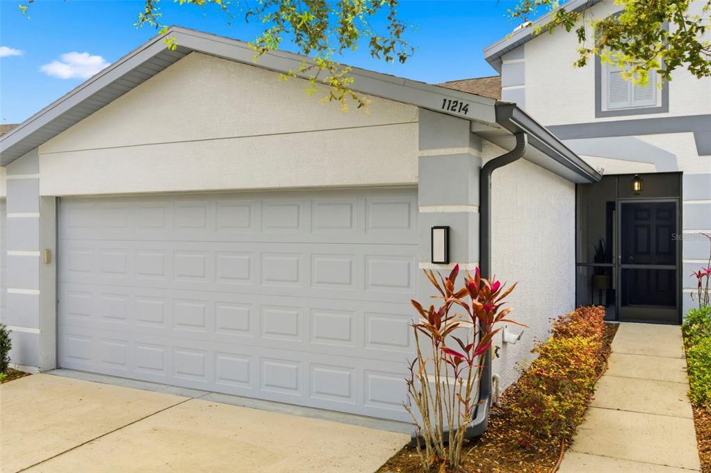 A view of a house exterior featuring a two-car garage and a front entryway — 11214 PORT DOUGLAS DRIVE, NEW PORT RICHEY, FL
