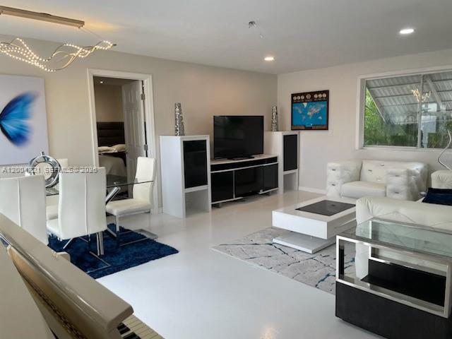 A modern living and dining area features white furniture, glossy floors, and a large television — 3219 Buckley Ave, Lake Worth FL 33461, LAKE WORTH, FL