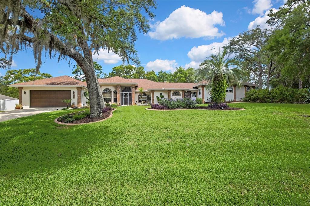 A single-story house with a brown roof, brick accents, and a large front lawn — 5701 W CHIVE LOOP, HOMOSASSA, FL
