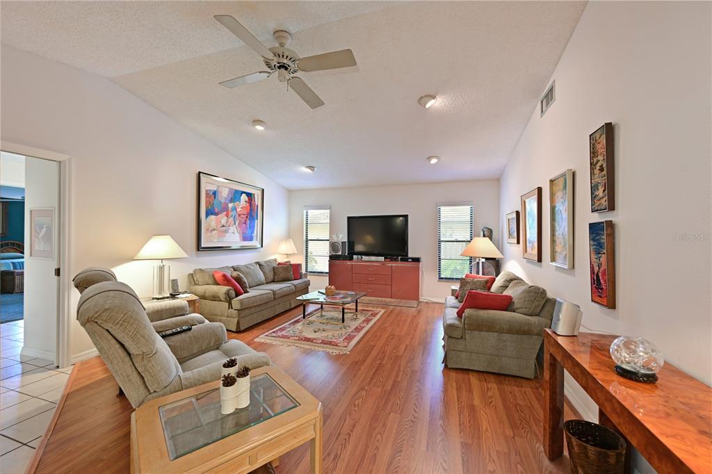 A living room features wood flooring, two sofas, a ceiling fan, and framed wall art — 4322 PASADENA COURT, SARASOTA, FL