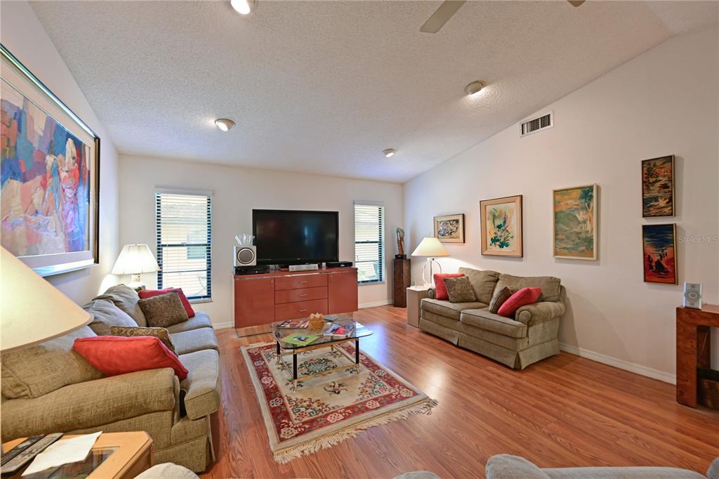 A living room features two tan sofas, a central coffee table, and wood-look flooring — 4322 PASADENA COURT, SARASOTA, FL