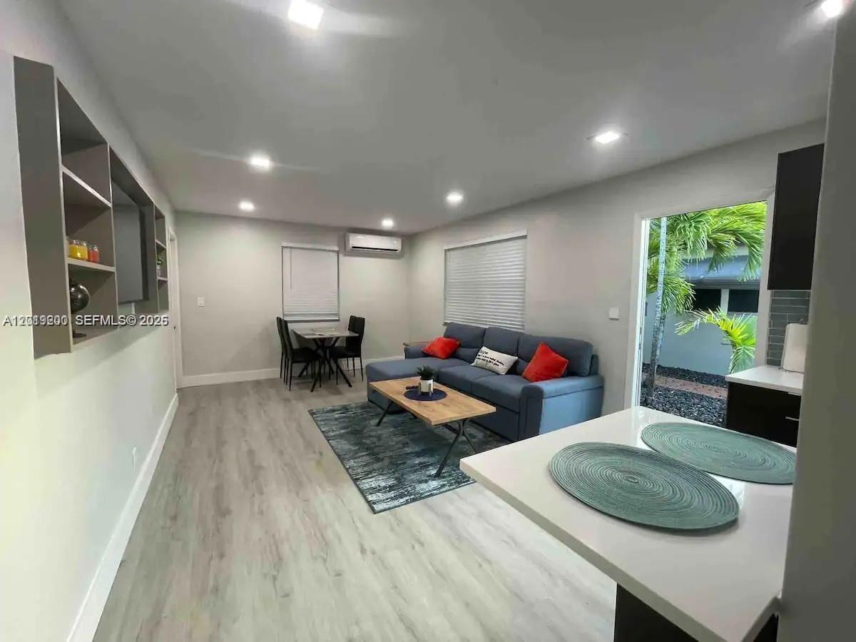 A living room features light wood flooring, a blue sectional sofa, and an open kitchen — 1925 Dewey St # 1927, Hollywood FL 33020, HOLLYWOOD, FL