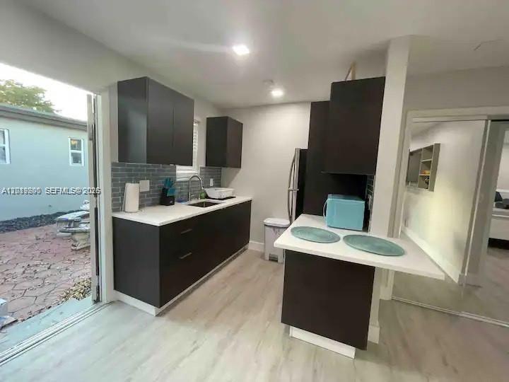 A modern kitchen features dark cabinetry, white countertops, a gray tiled backsplash, and light flooring — 1925 Dewey St # 1927, Hollywood FL 33020, HOLLYWOOD, FL