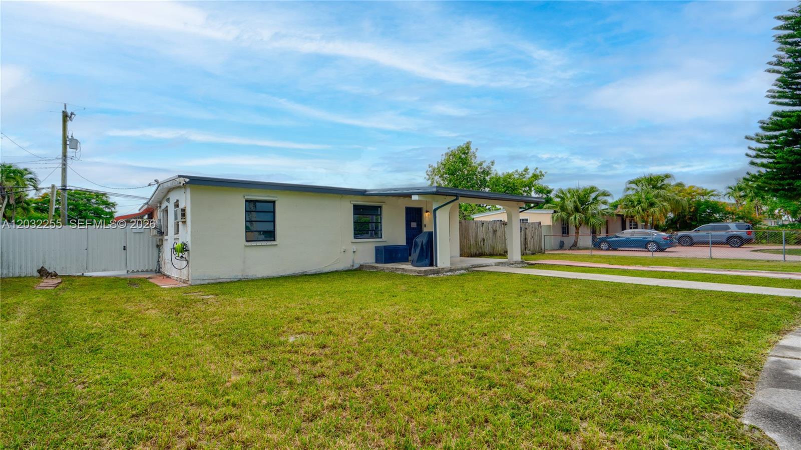 A single-story house with a covered porch sits on a grassy lot under a sky — 9840 SW 48th St, Miami FL 33165, MIAMI, FL