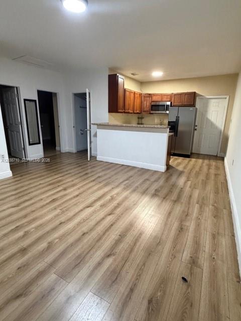 An open-concept kitchen with wood-look flooring features a breakfast bar and stainless steel appliances — HIALEAH, FL