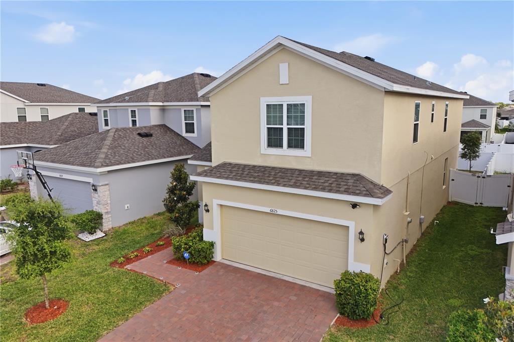 An exterior view of a two-story beige house with a brick driveway and garage — 6825 WILSON HAMMOCK AVENUE, GROVELAND, FL