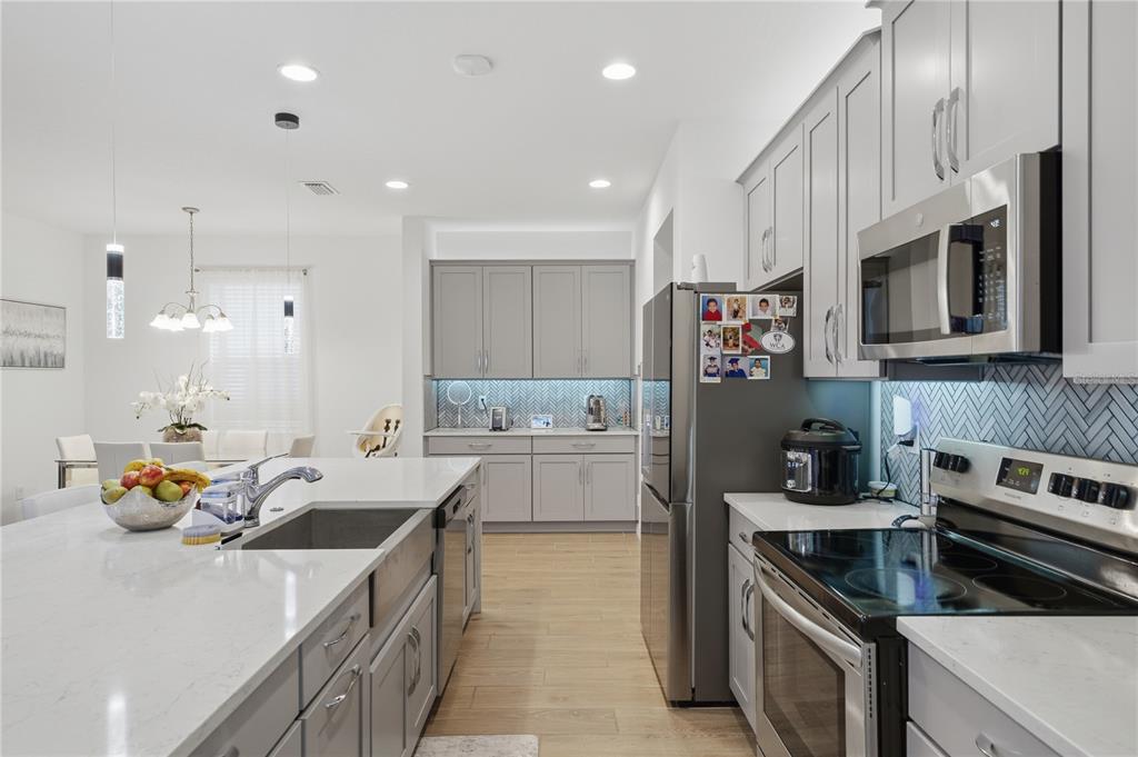 A modern kitchen features gray cabinetry, stainless steel appliances, and a large white quartz island — 6825 WILSON HAMMOCK AVENUE, GROVELAND, FL