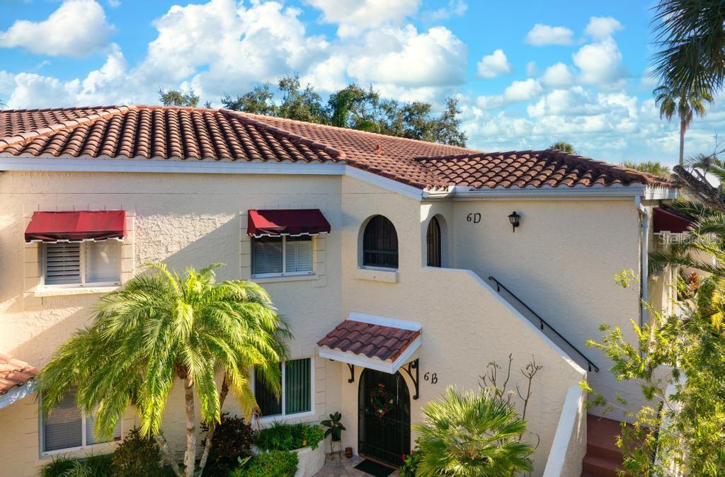 An exterior view of a two-story stucco building with a tiled roof and palm trees — 6101 W 34TH STREET W UNIT 6D, BRADENTON, FL