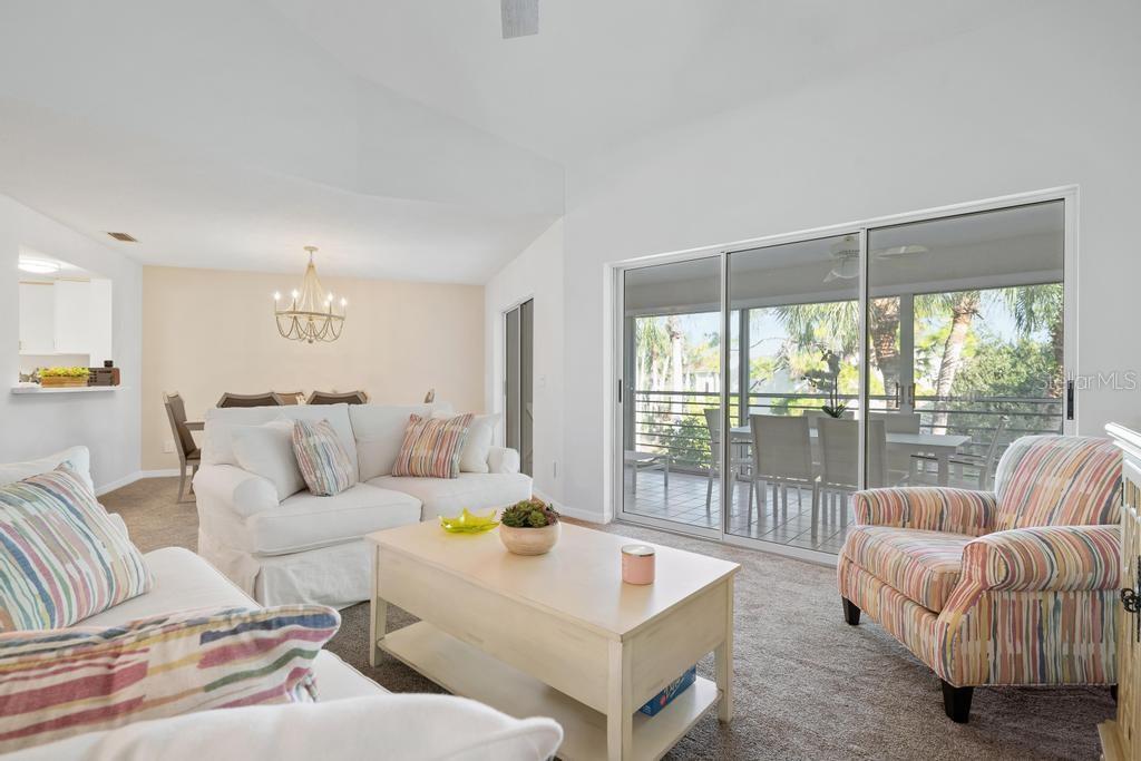 A living room features white sofas, a striped armchair, a coffee table, and sliding glass doors — 6101 W 34TH STREET W UNIT 6D, BRADENTON, FL