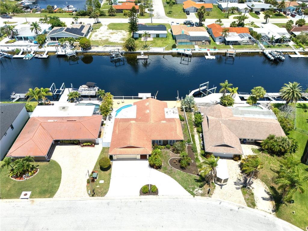 An aerial view shows three waterfront houses with tile roofs and private boat docks — 3517 SEAWAY DRIVE, NEW PORT RICHEY, FL