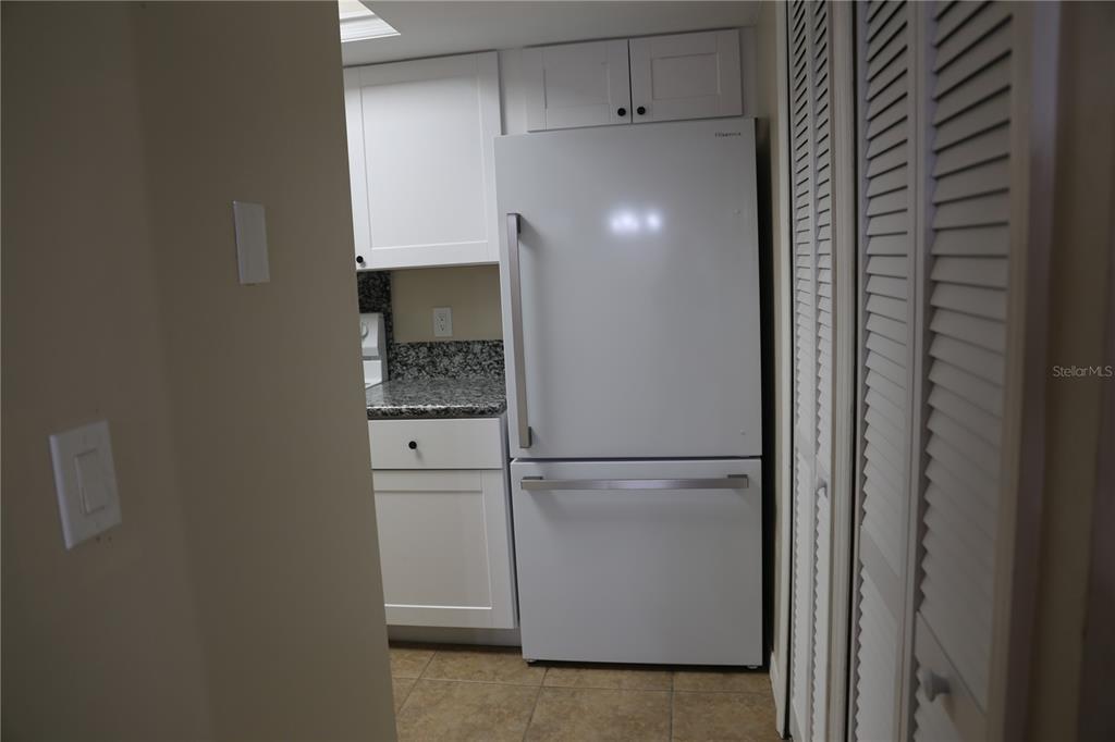 A white bottom-freezer refrigerator stands in a kitchen with white cabinets and granite countertops — 5831 SW 9TH PLACE, GAINESVILLE, FL