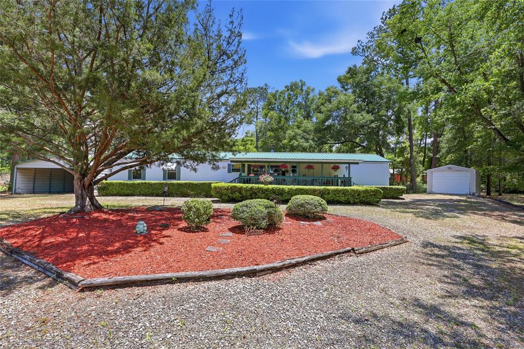 A single-story house with a green metal roof, a front porch, and a detached garage — 20480 COUNTY ROAD 137, LAKE CITY, FL
