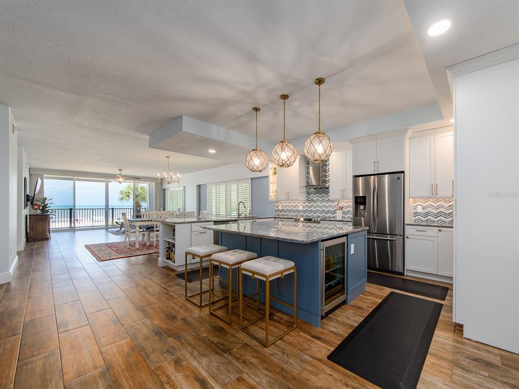 A kitchen with a blue island and pendant lights opens to a dining area and balcony — 19600 GULF BOULEVARD UNIT 102, INDIAN SHORES, FL