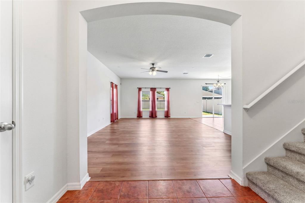 An entryway with tiled floors leads into a spacious living area with wood-look flooring — 10257 NEWMINSTER LOOP, RUSKIN, FL