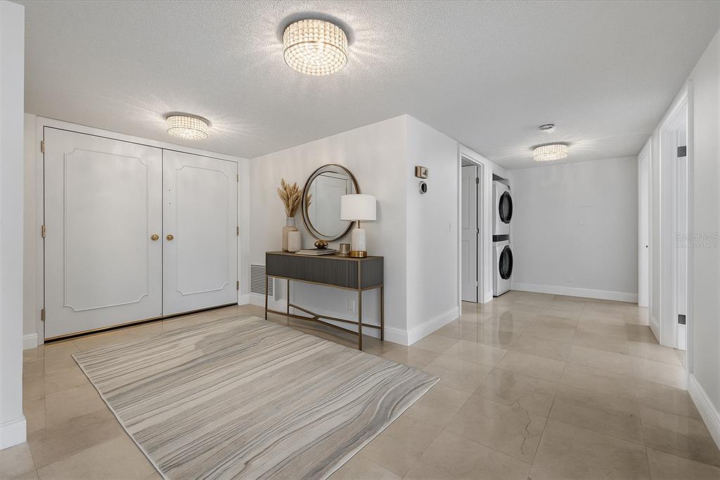 A bright entryway features a console table, a circular mirror, and a light-colored area rug — 100 OAKMONT LANE UNIT 101, BELLEAIR, FL
