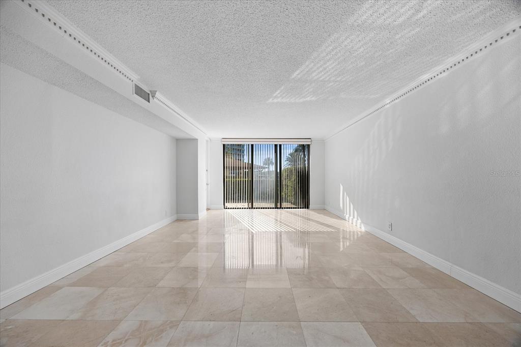 An empty room with light-colored tile flooring, white walls, and floor-to-ceiling sliding glass doors — 100 OAKMONT LANE UNIT 101, BELLEAIR, FL