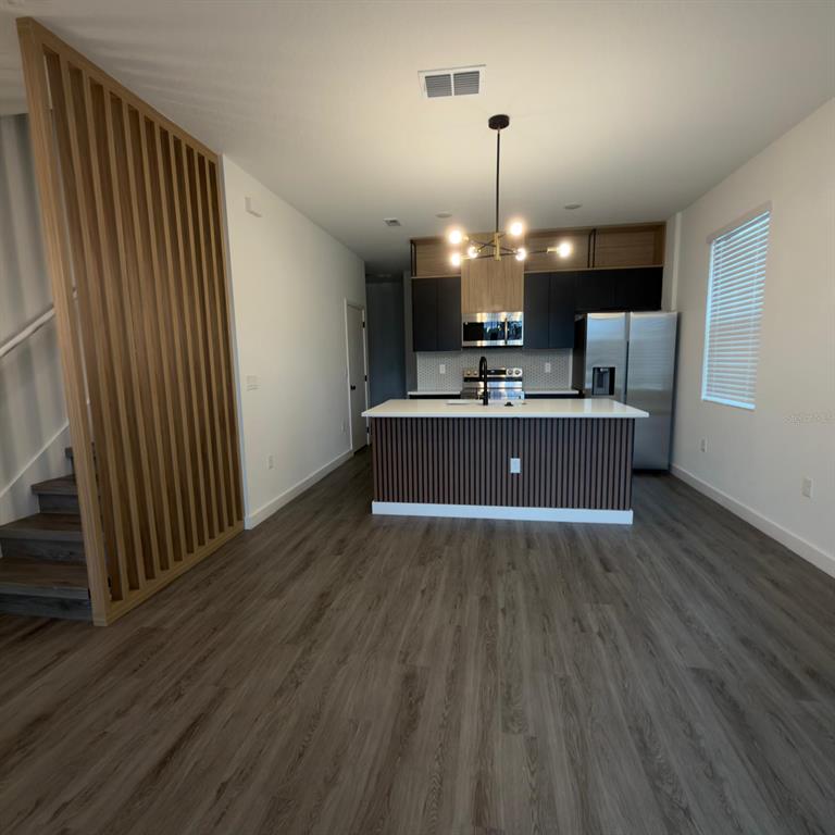 A kitchen with a center island, dark cabinetry, and a wood-slat staircase partition — 3229 ENERGY DRIVE, KISSIMMEE, FL
