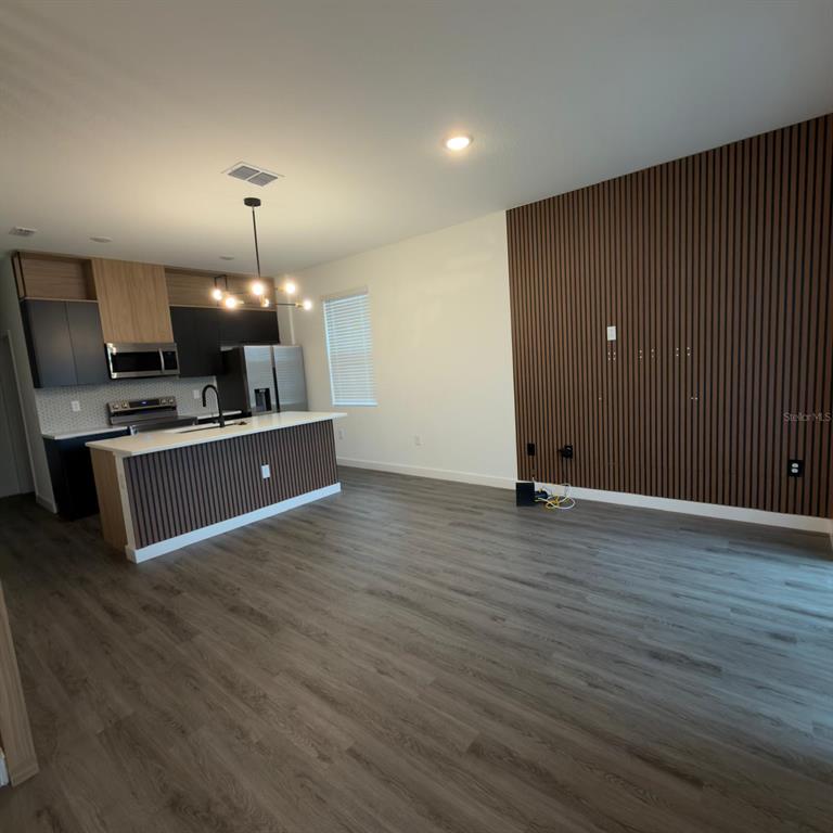 A kitchen with dark cabinets and a wood-slat island opens to a living area — 3229 ENERGY DRIVE, KISSIMMEE, FL