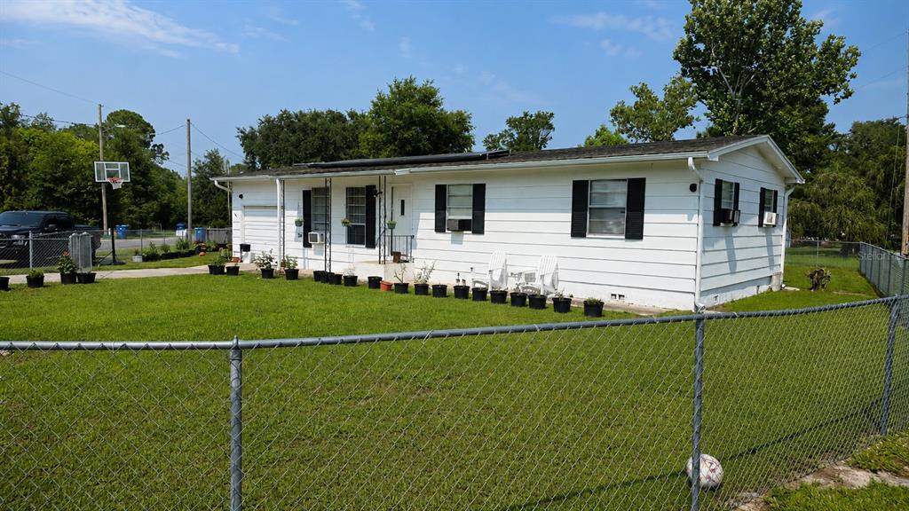 A white single-story house with black shutters sits behind a chain-link fence on a grassy lot — 354 PARK DRIVE, DELAND, FL