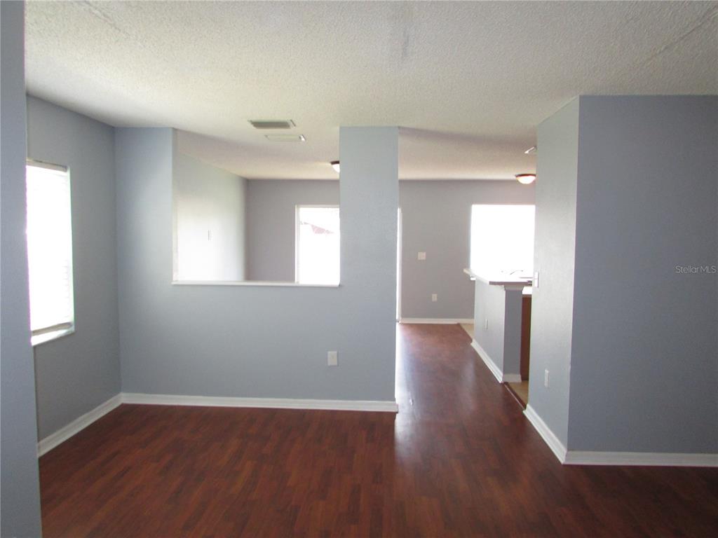 A living area with light blue walls, dark wood flooring, and a partial wall divider — 8532 EDGEWATER PLACE BOULEVARD, TAMPA, FL