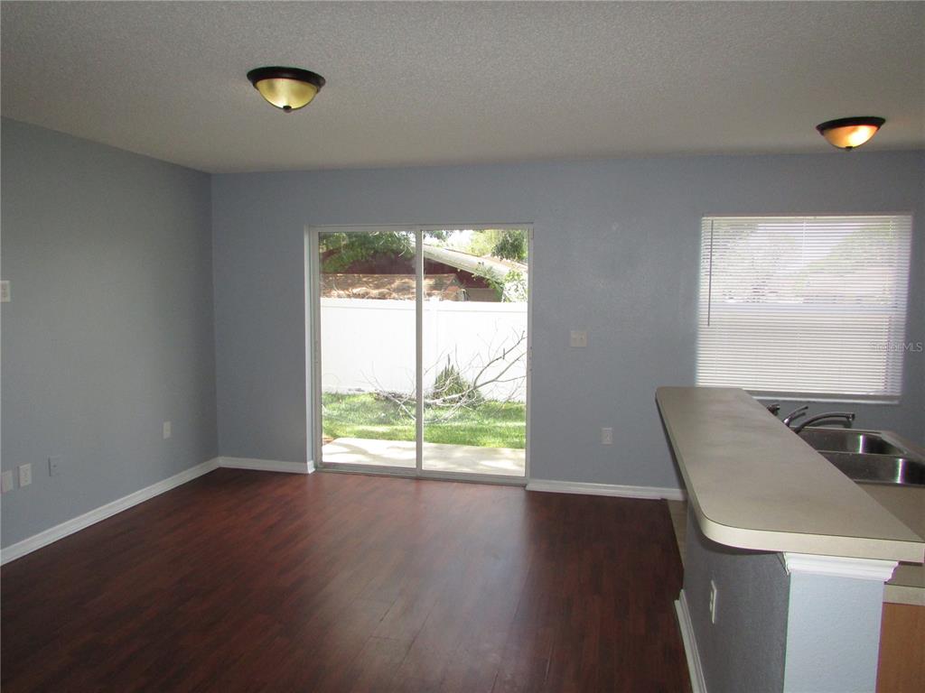 A dining area with dark wood floors, sliding glass doors, and a kitchen breakfast bar — 8532 EDGEWATER PLACE BOULEVARD, TAMPA, FL