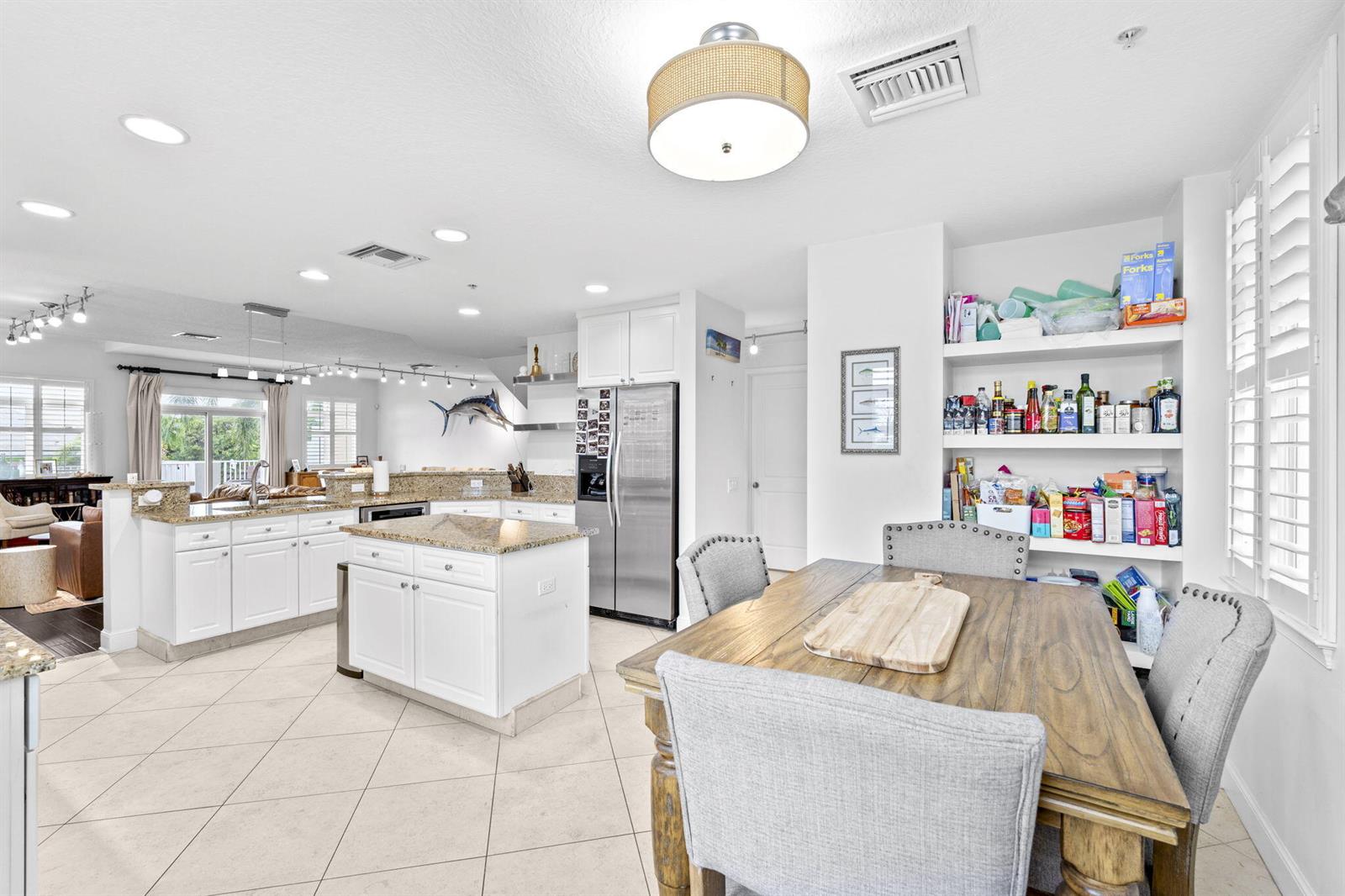 A kitchen with white cabinets, granite countertops, and an island next to a dining area — 305 E Ocean Avenue # 7, Lantana FL 33462, LANTANA, FL