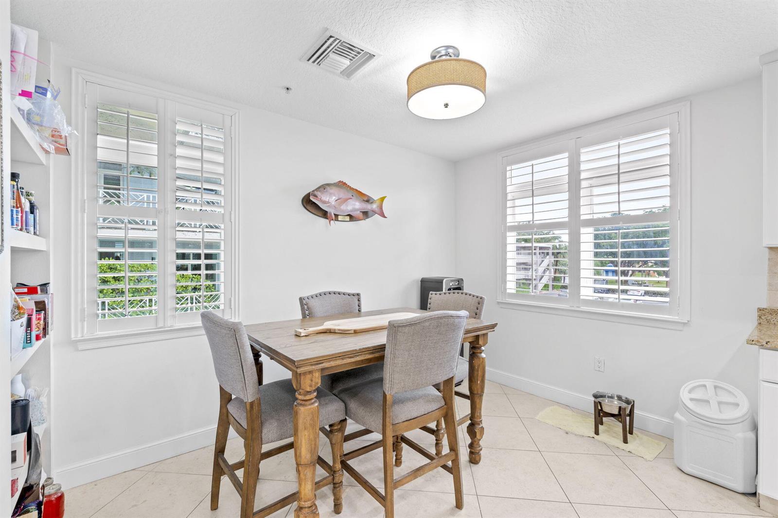 A dining area features a wooden table with four grey chairs and a fish mount — 305 E Ocean Avenue # 7, Lantana FL 33462, LANTANA, FL
