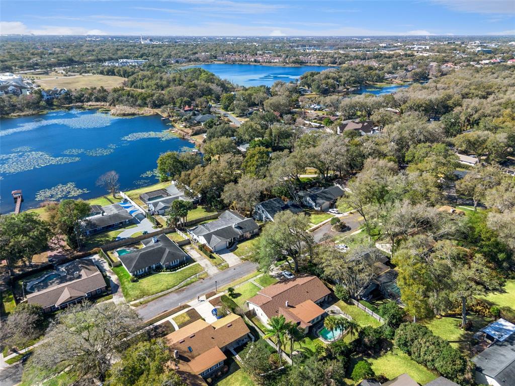 An aerial view shows suburban houses with swimming pools situated near a large lake — 448 STONEWOOD LANE, MAITLAND, FL